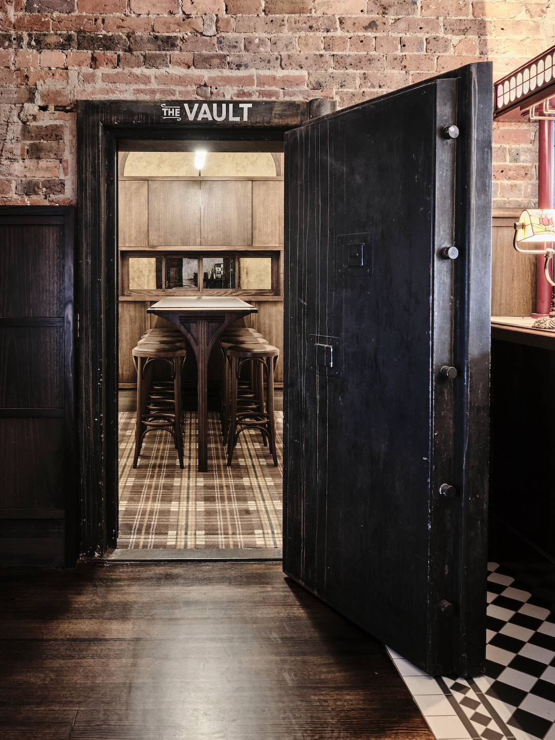 Chubb Massive Iron Security Door Leading to Secluded Room Plaid Carpet Pattern Timber High Table Stools Exposed Clay Masonry in The Bay Hotel. Photo by James Geer.