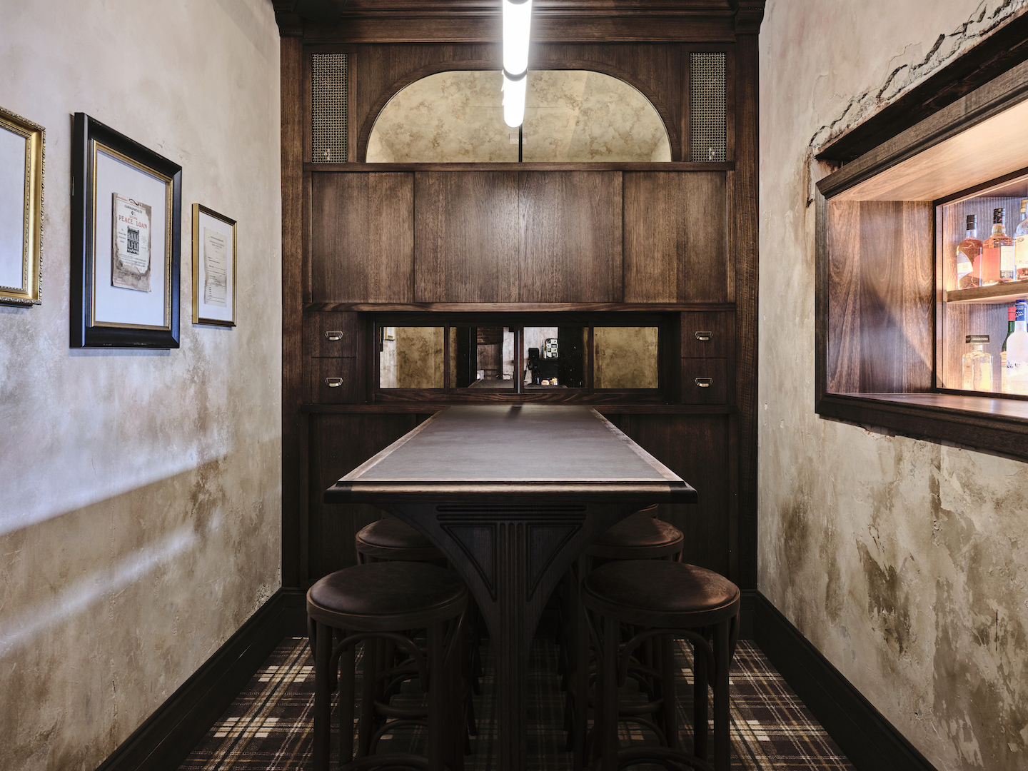 Ornate Dark Timber Alcove with Tall Trestle Bench Bentwood Round Stools Plaid Floor Covering Patina Wall Texture Heritage Nook in The Bay Hotel. Photo by James Geer.