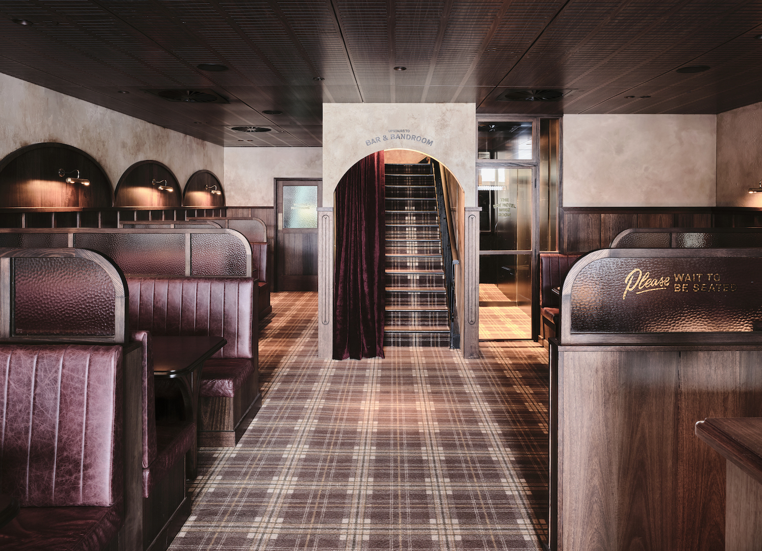 Burgundy Leather Booths with Hammered Glass Dividers Plaid Floor Arched Staircase Entry Velvet Drapes Heritage Pub Interior in The Bay Hotel. Photo by James Geer.
