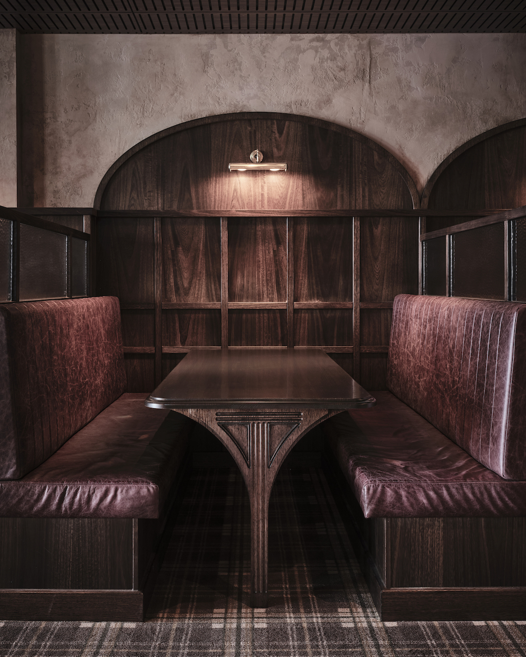 Burgundy Leather Banquettes Arched Timber Wall Paneling Custom Trestle Table Brass Picture Light Textured Plaster Walls in The Bay Hotel. Photo by James Geer.