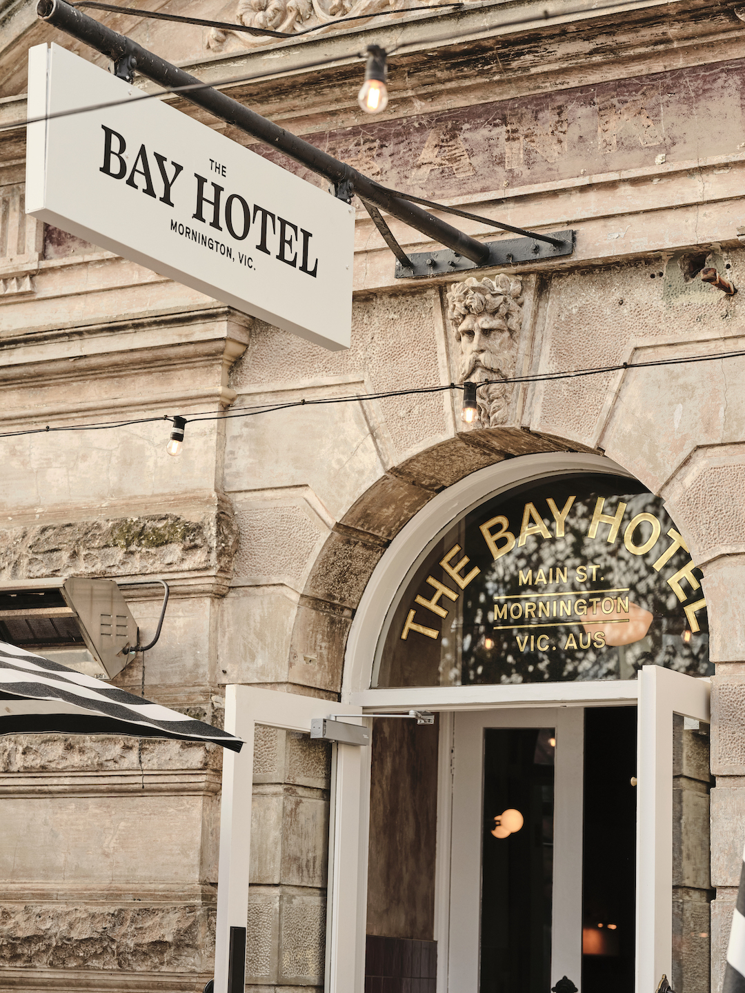 Historic Sandstone Facade Projecting Exterior Identifer Arched Entryway Gold Leaf Window Lettering Ornate Stone Carvings in The Bay Hotel. Photo by James Geer.
