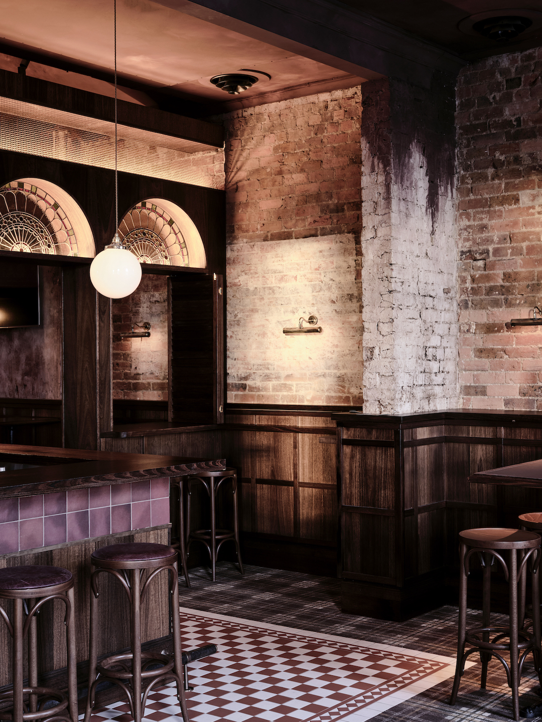 Exposed Red Brick Pillars Walnut Wall Paneling Stained Glass Arch Details Bentwood Barstools and Tiled Flooring Textures in The Bay Hotel. Photo by James Geer.