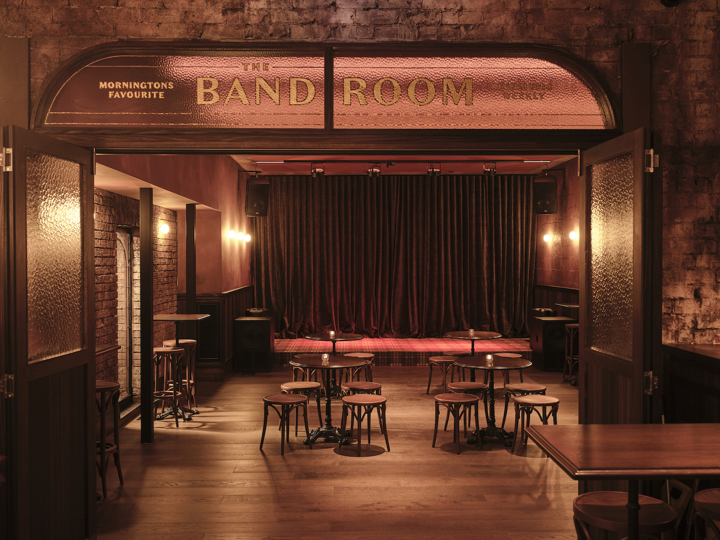 Gold Leaf Arched Entry Signage Overlooking Performance Space Velvet Curtains Stage Area Bentwood Stools and Warm Ambient Lighting in The Bay Hotel. Photo by James Geer.