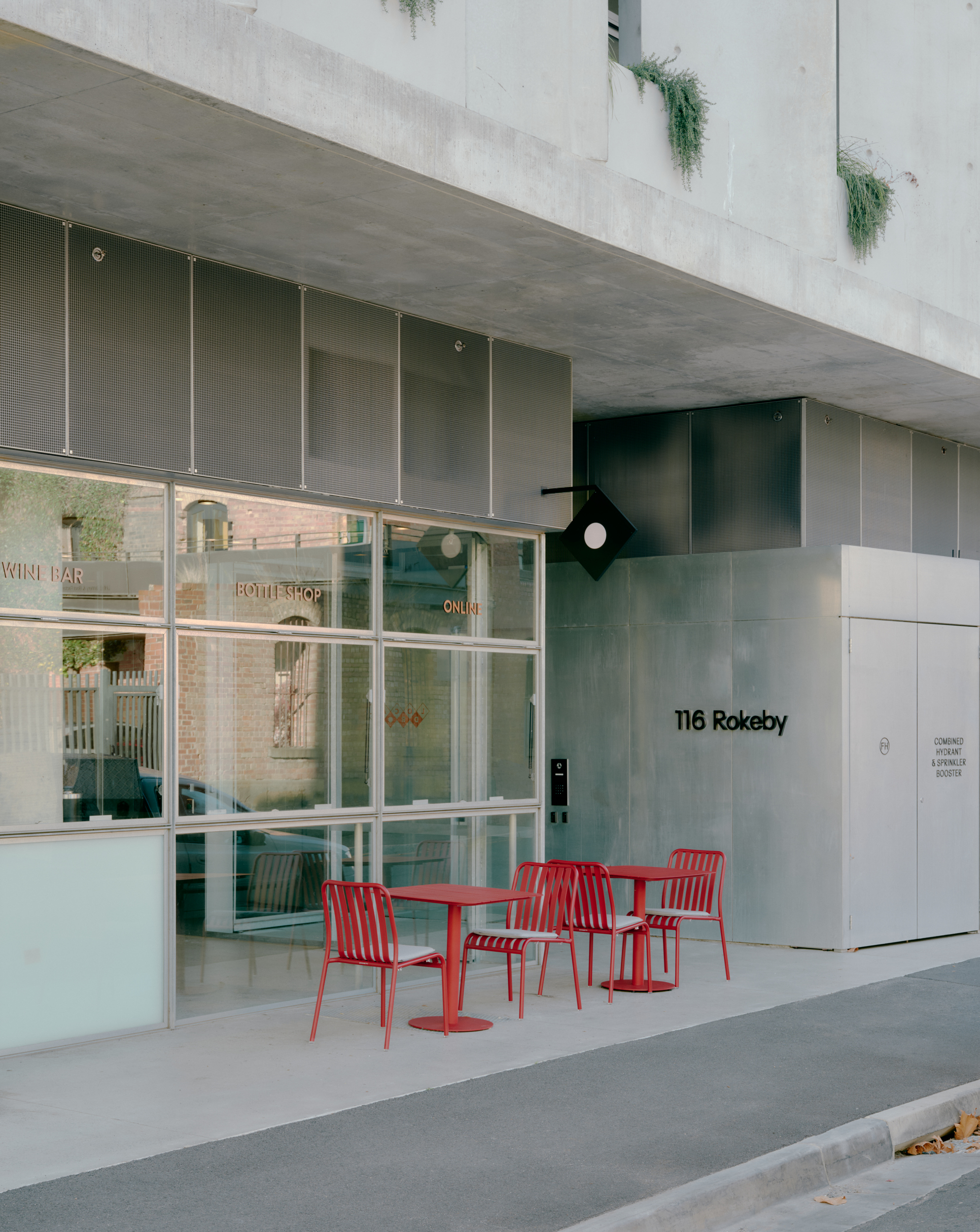 Modern Industrial Exterior at 116 Rokeby with Red Bistro Seating Glass Facade Mesh Bulkhead and Diamond Blade Signage in The Local Drop. Photo by Pier Carthew and Kevin McDowell.