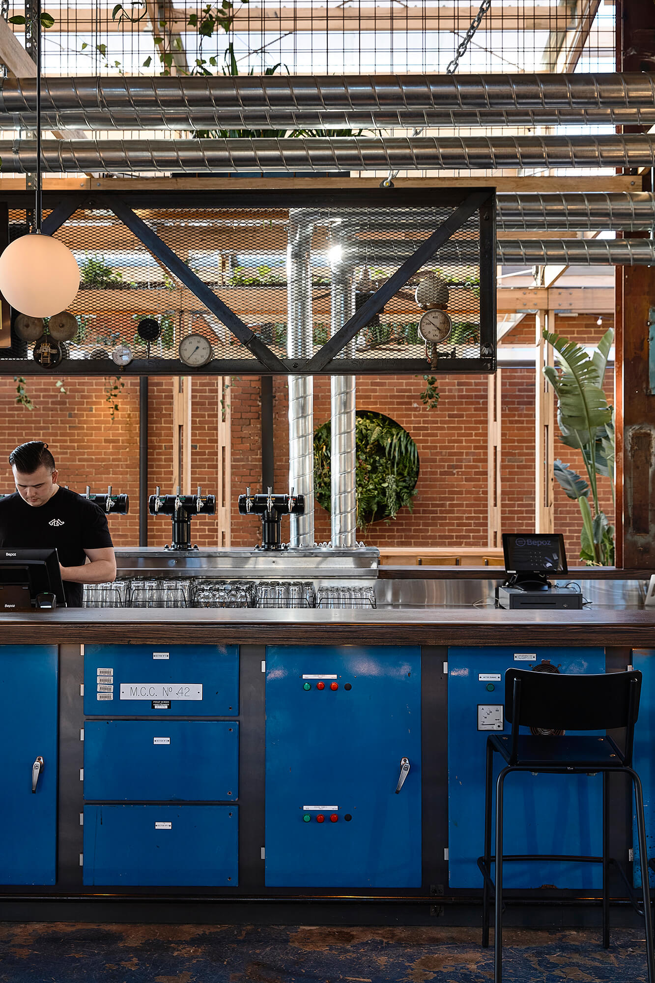 Industrial Bar with Blue Machinery-Style Cabinetry Exposed Ducting Steel Mesh Bulkhead and Beer Taps in Stomping Ground Morris Moor. Photo by Derek Swalwell.