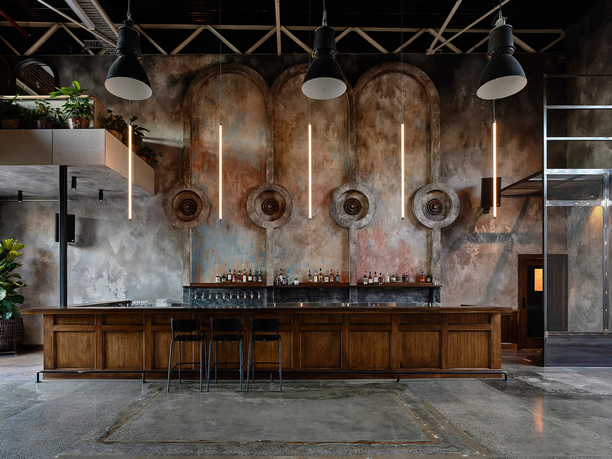 Wide View of Grand Timber Bar with Four Textured Arches Linear Pendants Industrial Dome Lights and Polished Concrete Floors in Stomping Ground Morris Moor. Photo by Derek Swalwell.