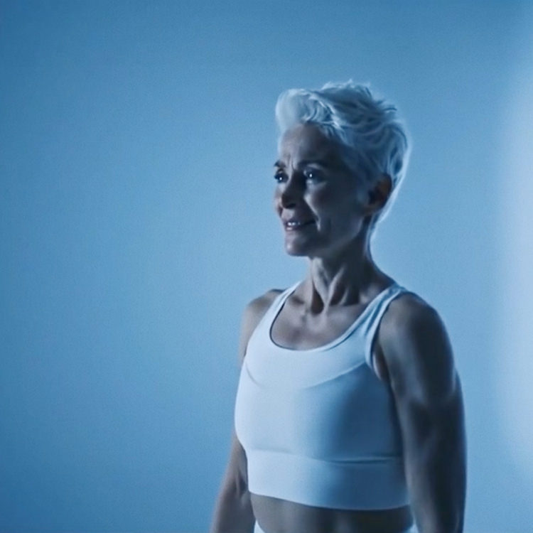 Elderly woman in white tank top looking focused in blue-lit studio