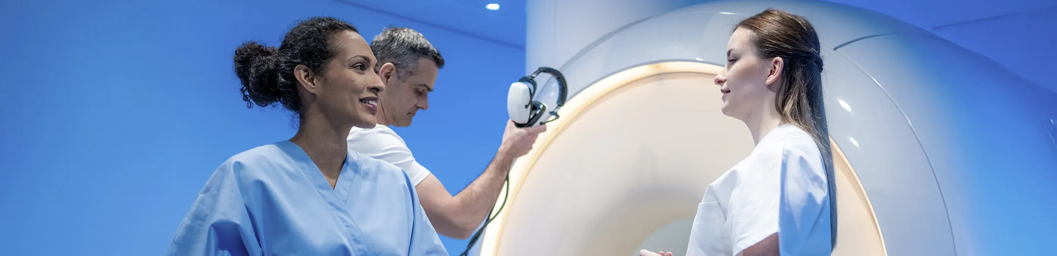 MRI technician preparing female patient for scan