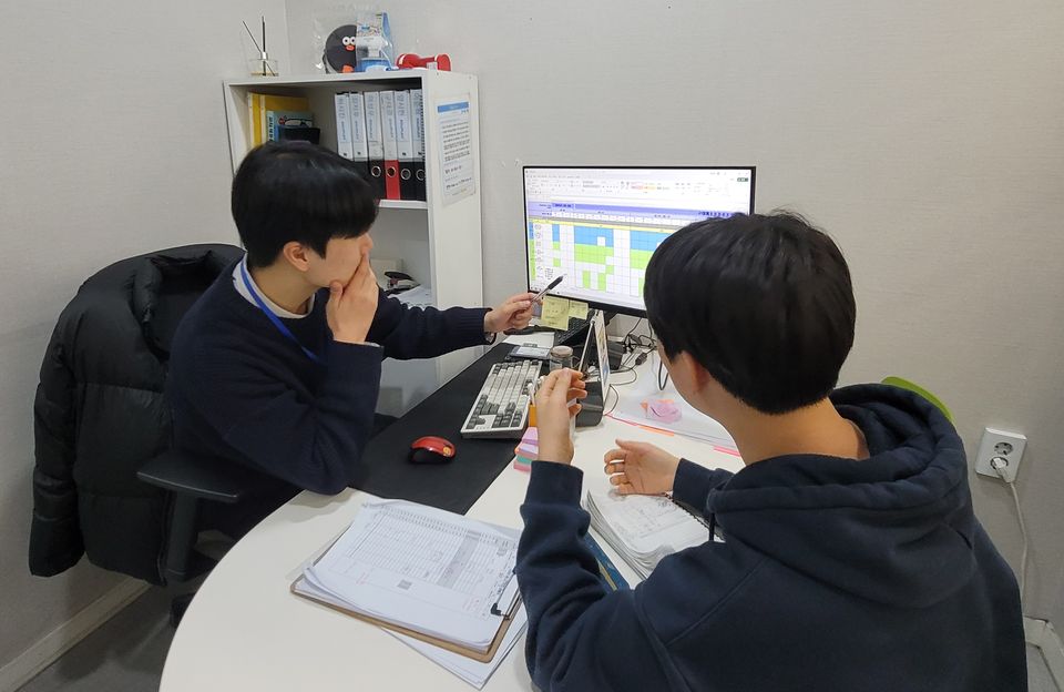 전담 코칭매니저와 학생이 모니터의 계획표를 함께 보며 상담하는 모습