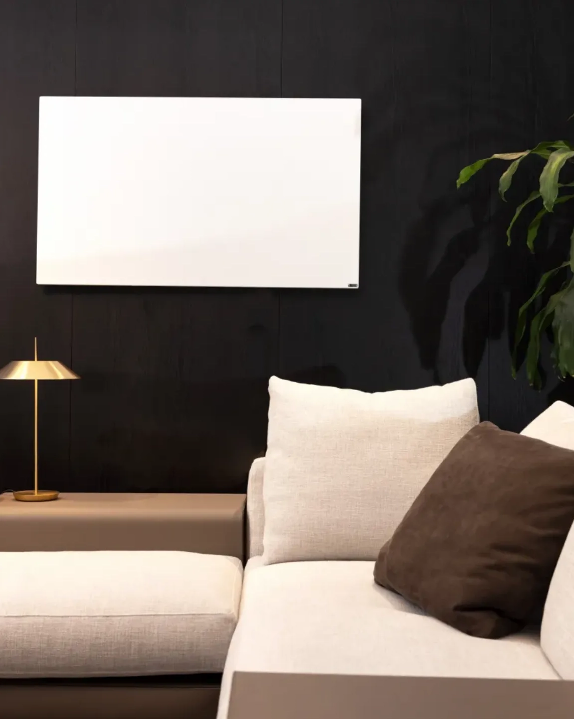 Hvidt rektangulært Redwell WE-Line infrarødt varmepanel monteret på en mørk væg over en lys sofa i en stilfuld, moderne stue.