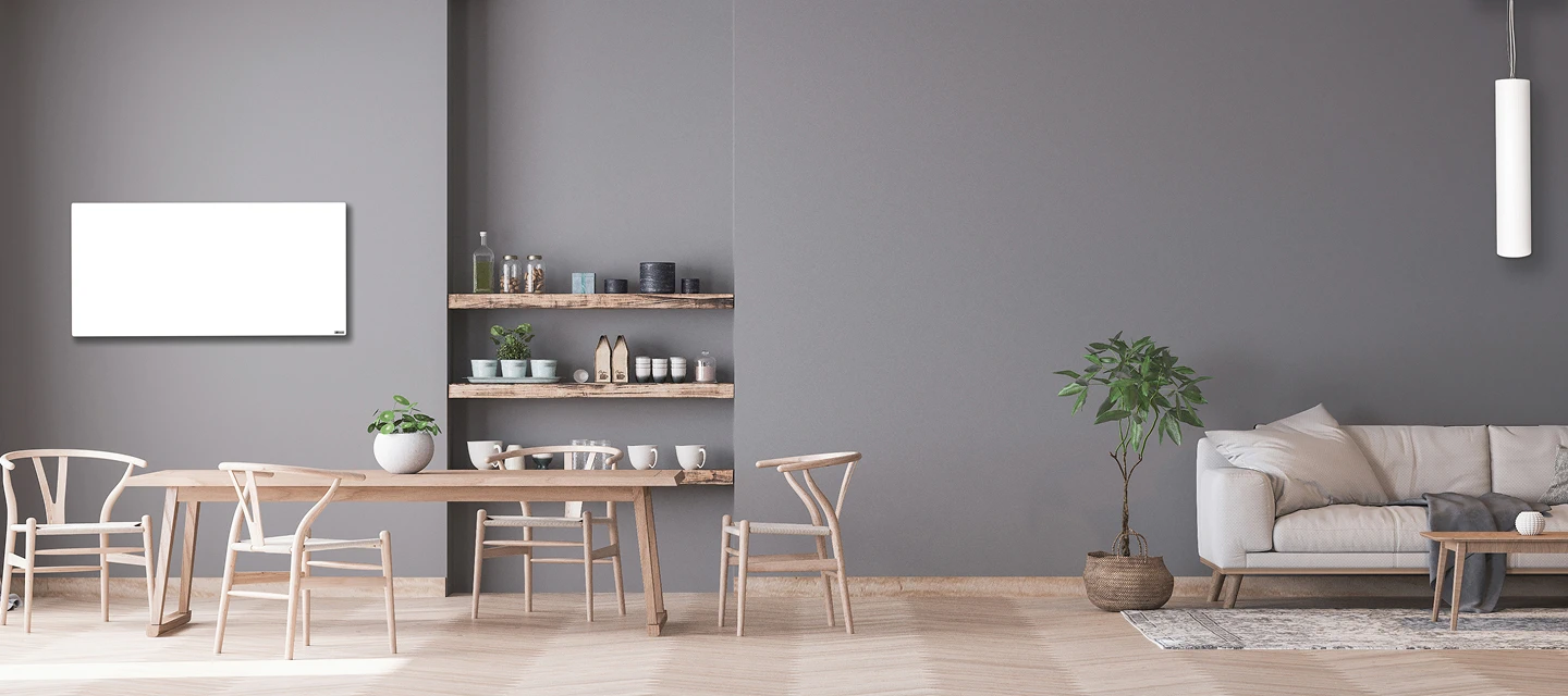 Diskret, hvidt rektangulært Redwell WE-Line infrarødt varmepanel monteret på en grå væg i et stort, moderne køkkenalrum med spisebord og sofa. Viser en æstetisk varmeløsning, der blender ind i indretningen.