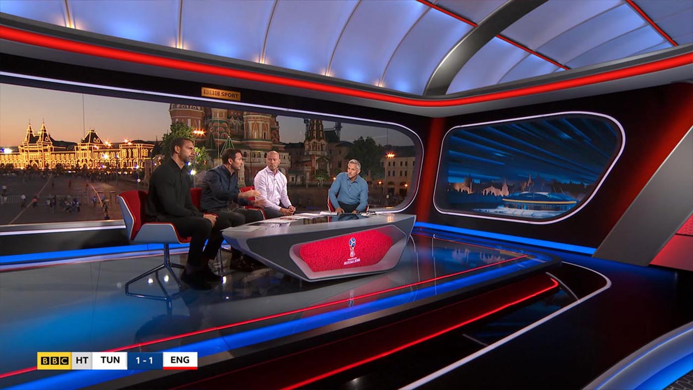 Gary Lineker presenting Match of the Day from the hybrid real and virtual set located in Red Square. In the background, it is night time, and outside we can see St Basils cathedral s