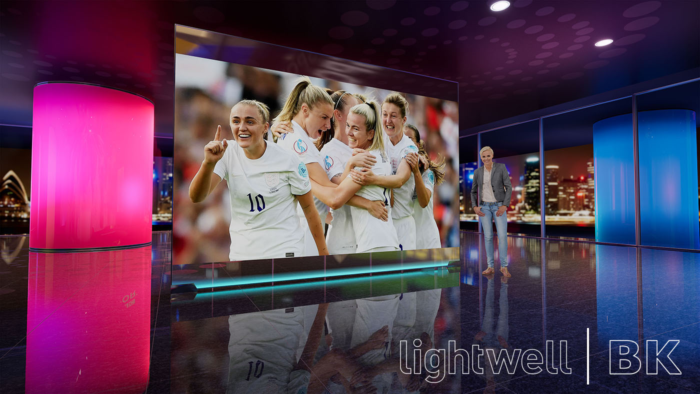 View of a standing presenter, at a large video screen from our design pitch for the BBC's coverage of the FIFA Womens World Cup in 2027