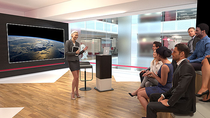 A wide shot of a presenter stood by a stool and lectern, addressing a small audience of invited guests. I don't know what she's talking about, but the audience look like they are enjoying it. In the background we see a virtual reproduction of the PWC interior atrium.
