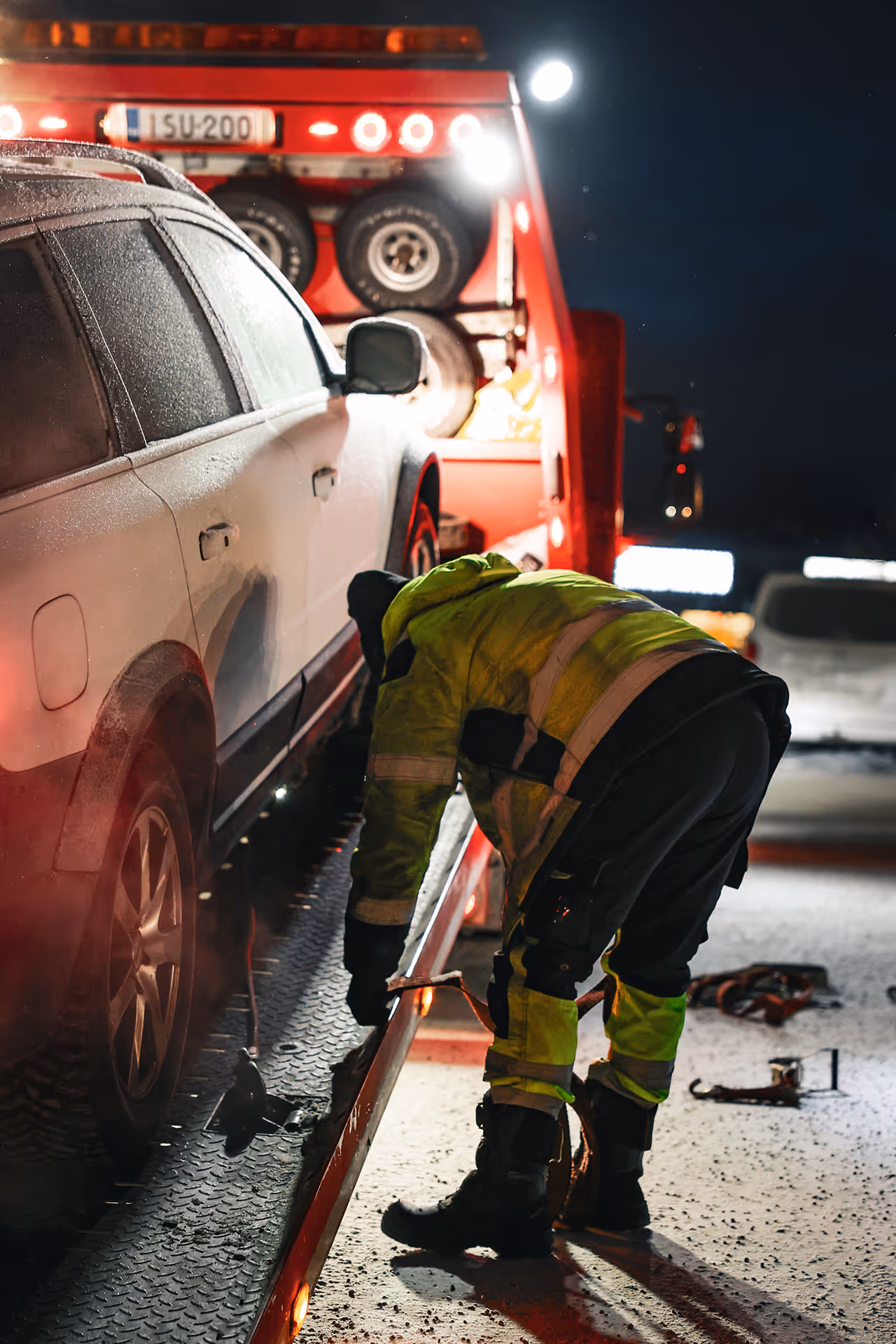 Henkilöauto kiinnitetään hinausauton lavalle talvi-iltana.