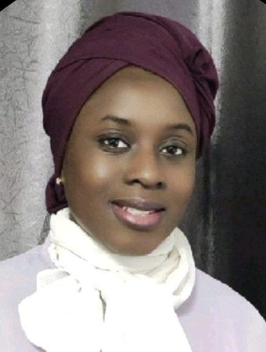 Portrait of a smiling woman wearing a maroon headwrap and a white scarf.