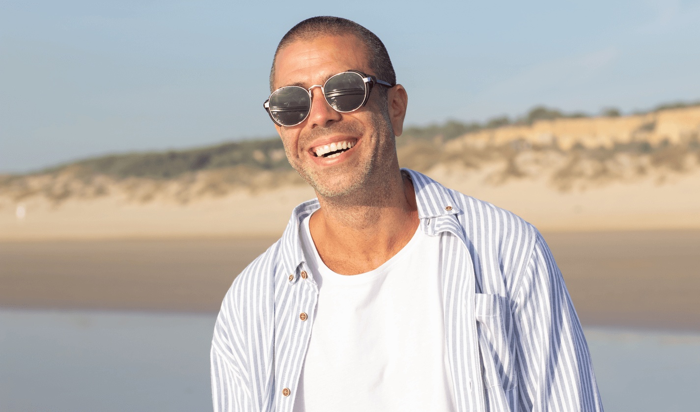 Smiling man enjoying the beach with a confident smile after getting the best dental implants in Miami Beach.