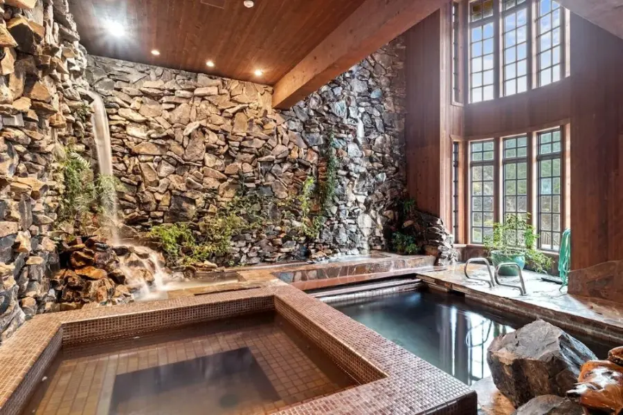 Indoor pool, hot tub, waterfall with two story windows at a luxury vacation rental in Anacortes, WA.