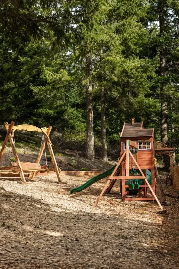 Kids playground with swings, slide, playhouse, and more plus a custom wood bench.