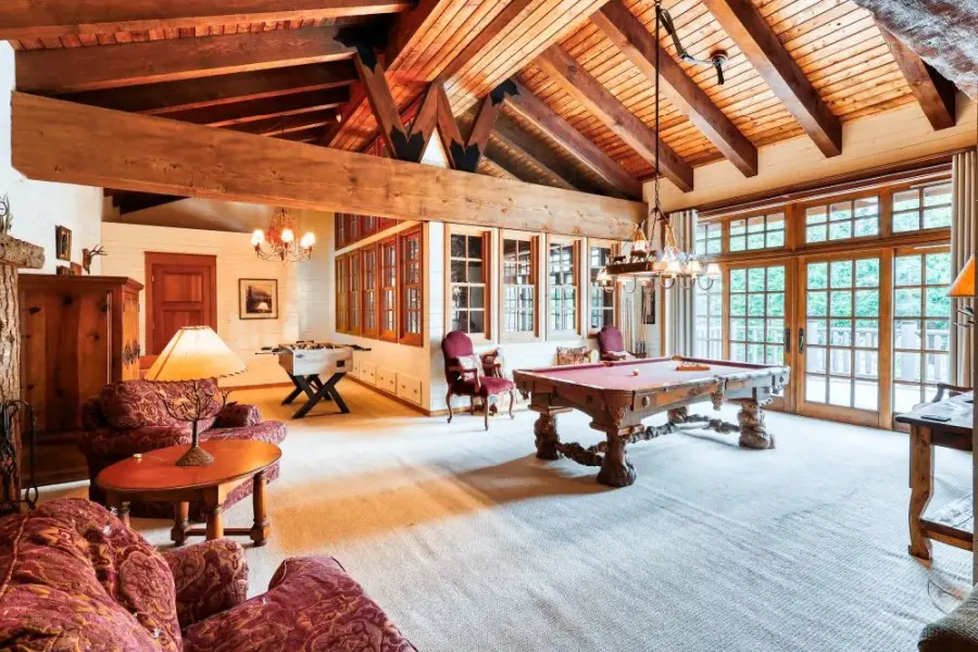 Vaulted wood ceilings with large wood beam overlooks a recreation room outfitted with pool table, foosball, and couches for socializing. Window views to the Puget Sound.