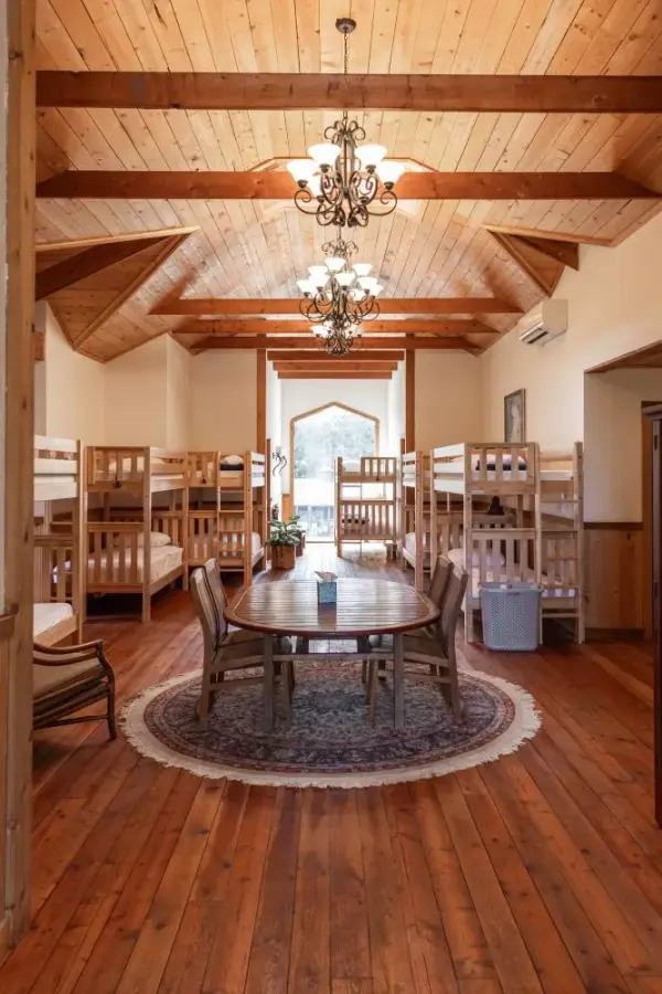 Large room with multiple bunk beds for overnight group lodging with a table and chairs for socializing.