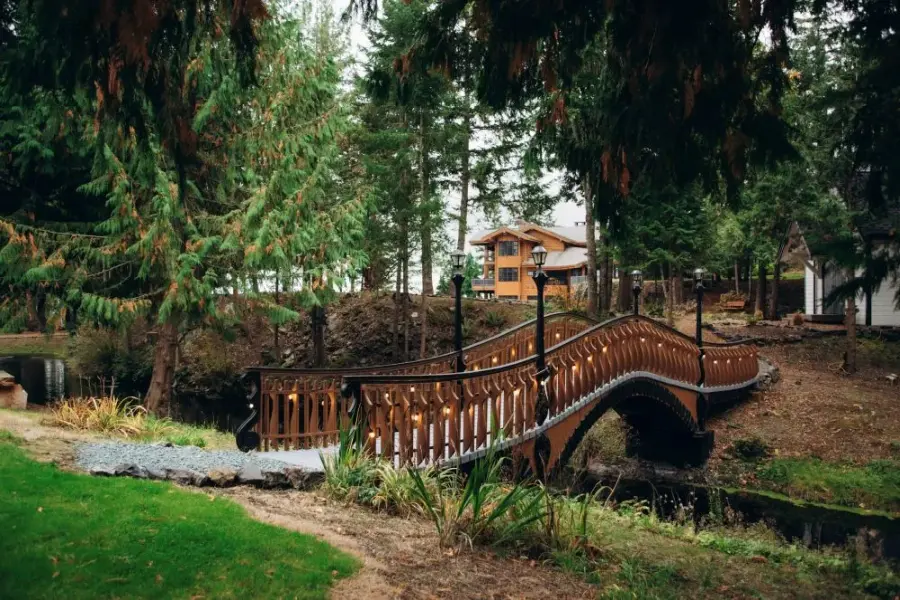 A custom-built wood bridge goes over a pond to a quaint white country chapel used as a wedding venue in Skagit County.