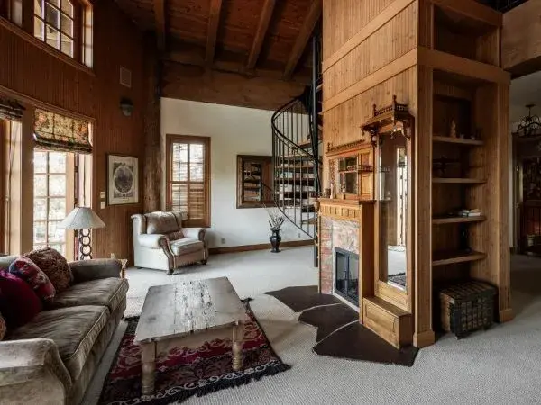 Private suite in a large lodge used for vacation rentals in Anacortes features a fireplace, spiral staircase, kitchenette, couch.