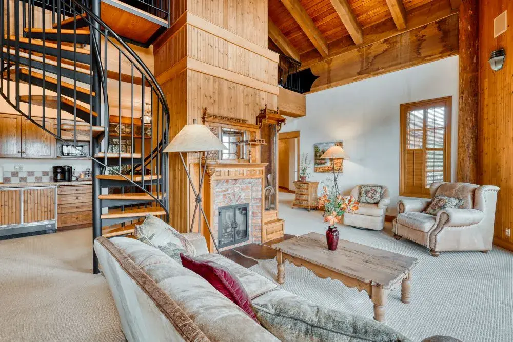 Black spiral staircase, kitchenette, fireplace, couches inside a private suite in a luxury vacation rental. 