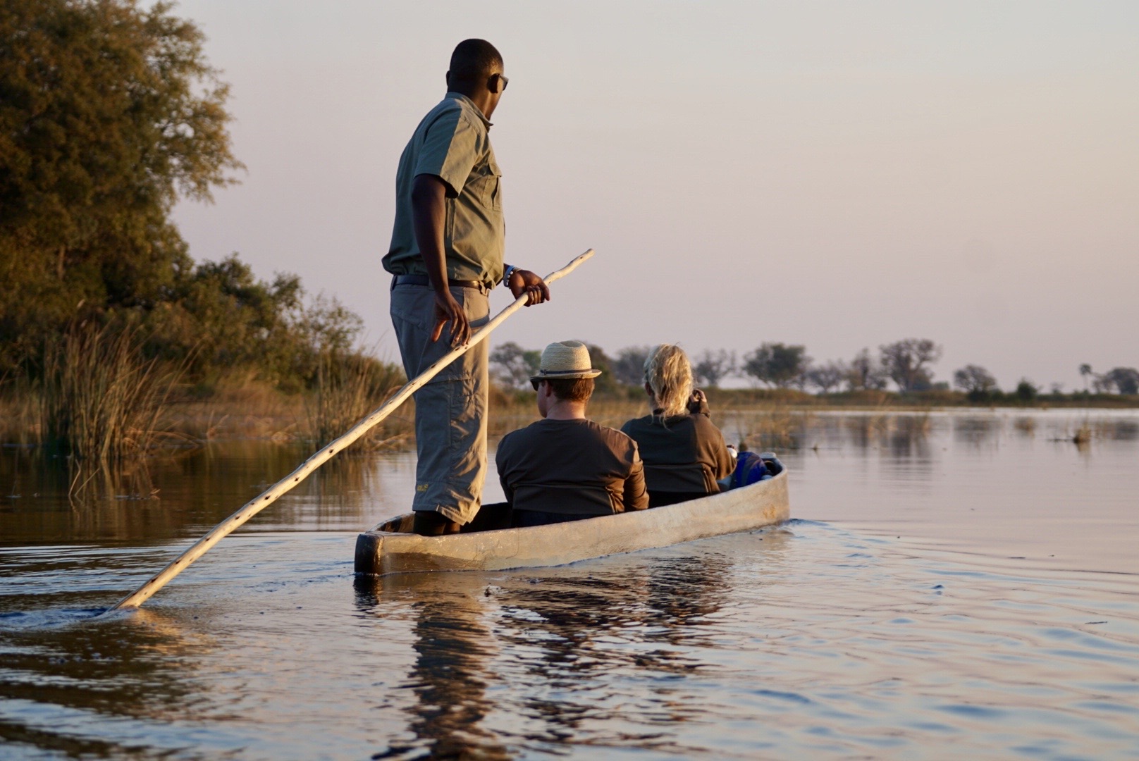 3 Menschen auf einem Mokoro auf dem Fluss in Sambia. 