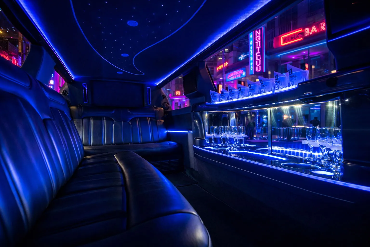 Interior of a limousine with blue LED lighting, leather seats, and glasses on a mirrored shelf.