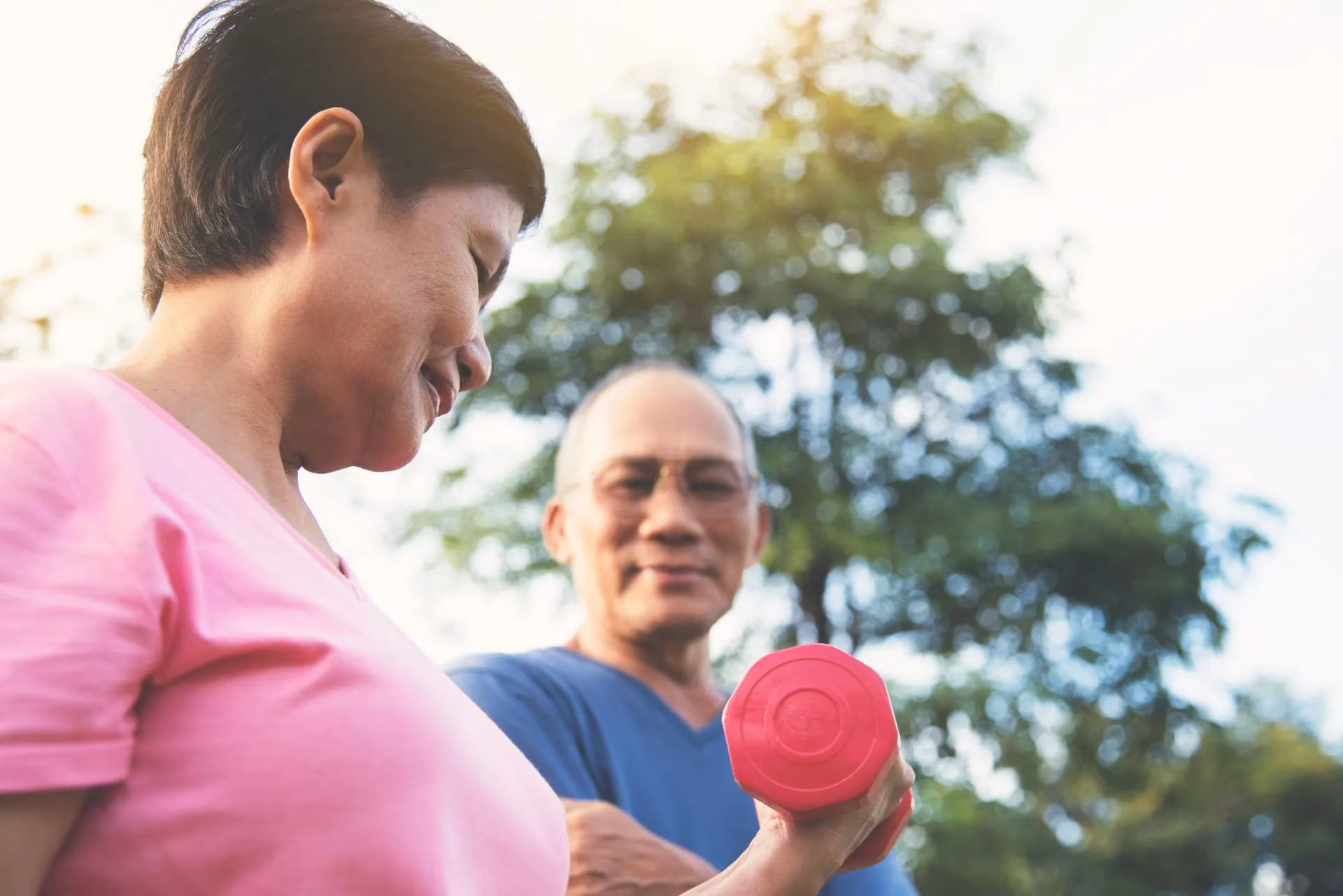 A man and woman holding a red weight. - Wellinks Images