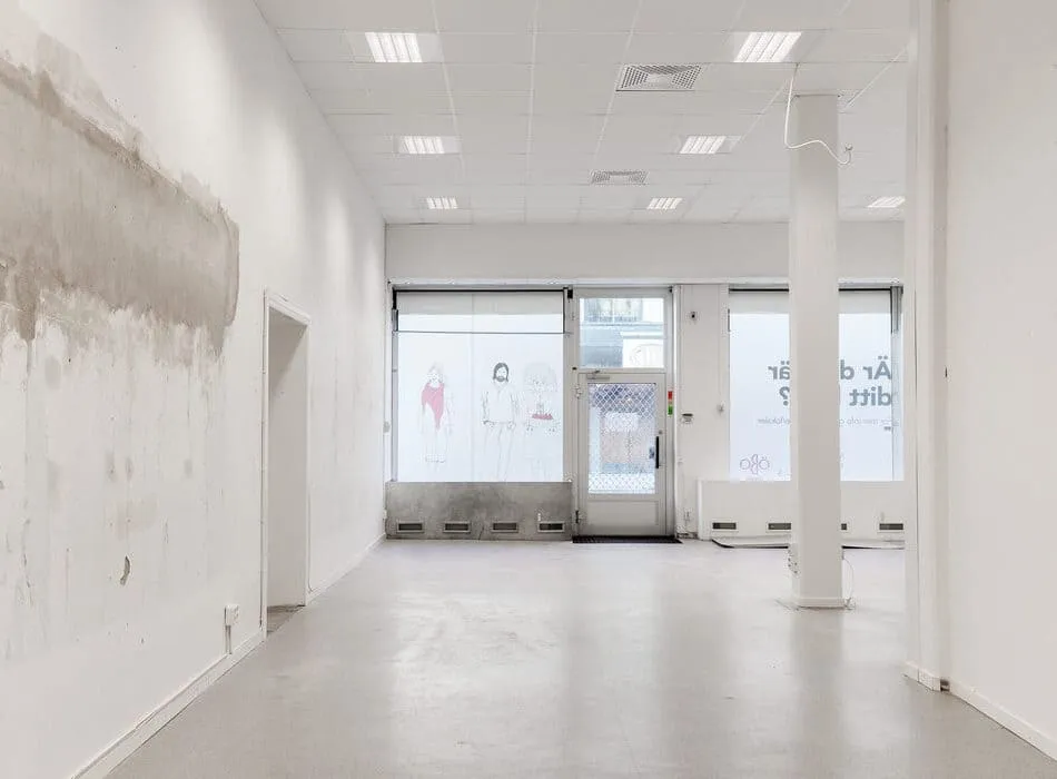 Real staging of an empty retail or commercial space with plain walls, exposed ceilings, and tiled flooring.