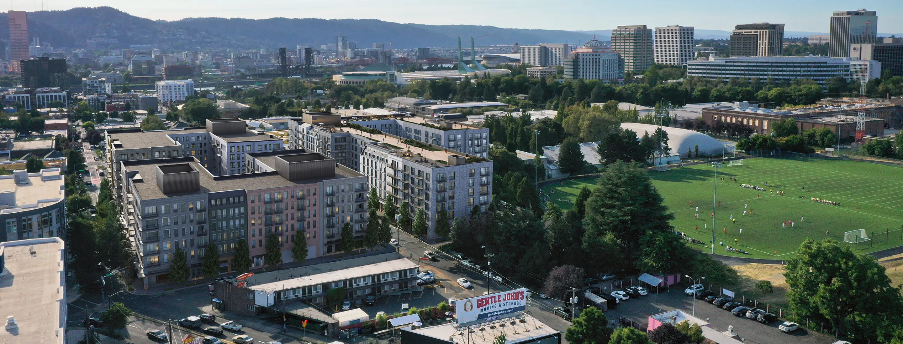 City planning rendering of a mixed-use urban development featuring mid-rise residential buildings adjacent to a community sports field, with tree-lined streets and a mix of commercial spaces in the foreground, integrating residential and recreational amenities within a city neighborhood.