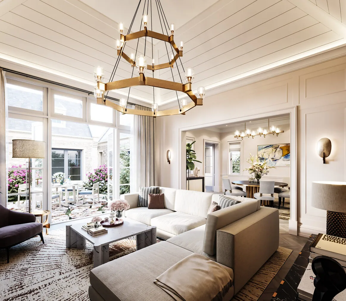 Luxurious open-concept living and dining room with a vaulted, wood-beamed ceiling, stone archways leading to a garden courtyard, a large blue sectional sofa, and elegant chandeliers.