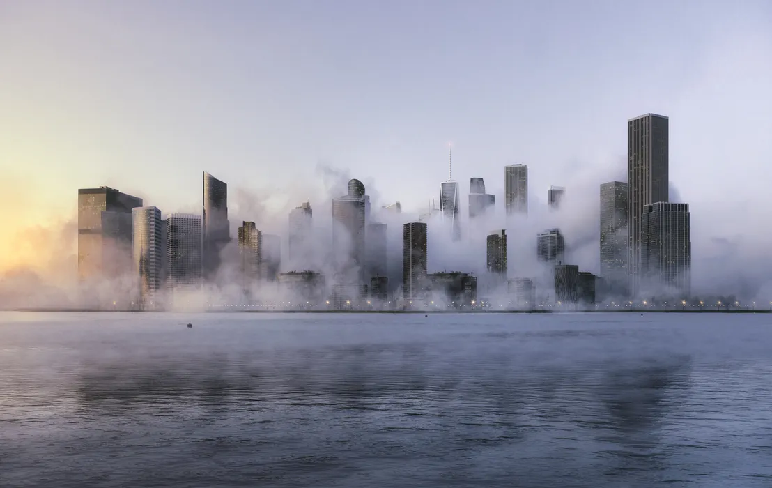 Skyscraper rendering of a fog-covered city skyline at sunrise with numerous towers emerging through the mist along a waterfront.
