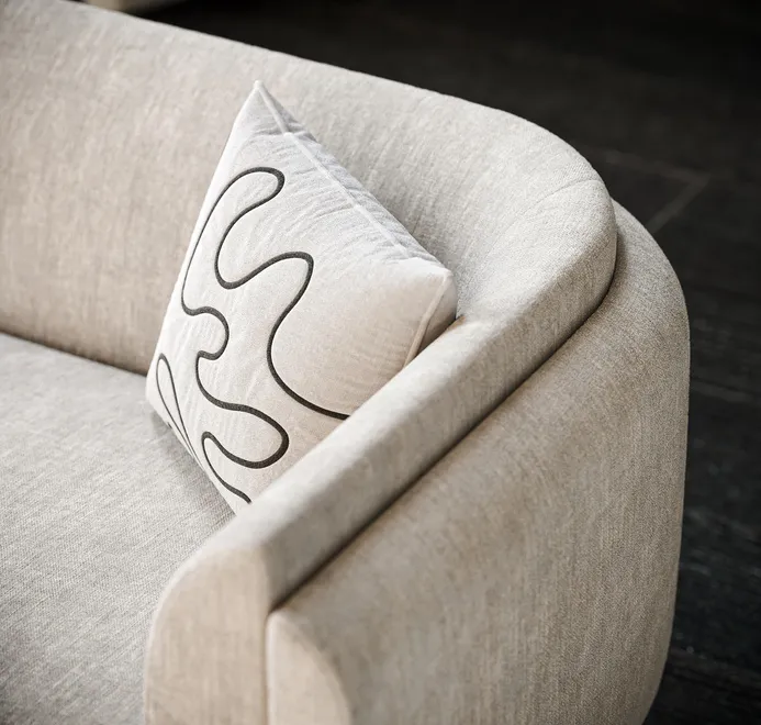 Close-up of a modern upholstered sofa with textured fabric and abstract accent pillow, created by a 3D Product Rendering Company Nashville.