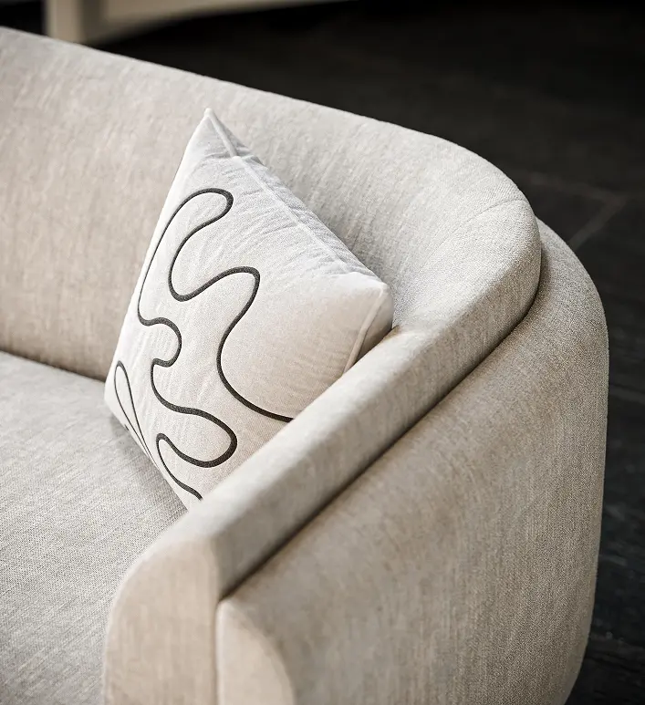  A close-up of a beige sectional sofa placed in a modern living room with polished concrete flooring and expansive glass windows, rendered in high-quality 3D product visualization.