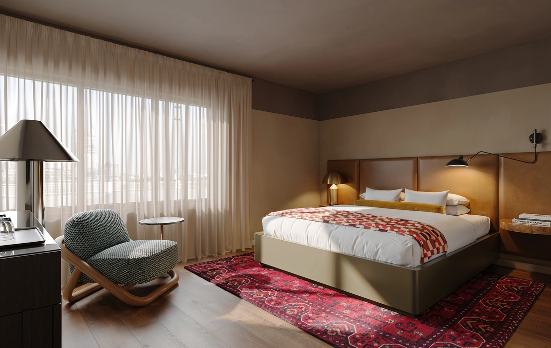 3d interior lighting rendering of a stylish hotel bedroom with soft daylight through sheer curtains, warm bedside lamps, a leather headboard, patterned red rug, and a cozy lounge chair.