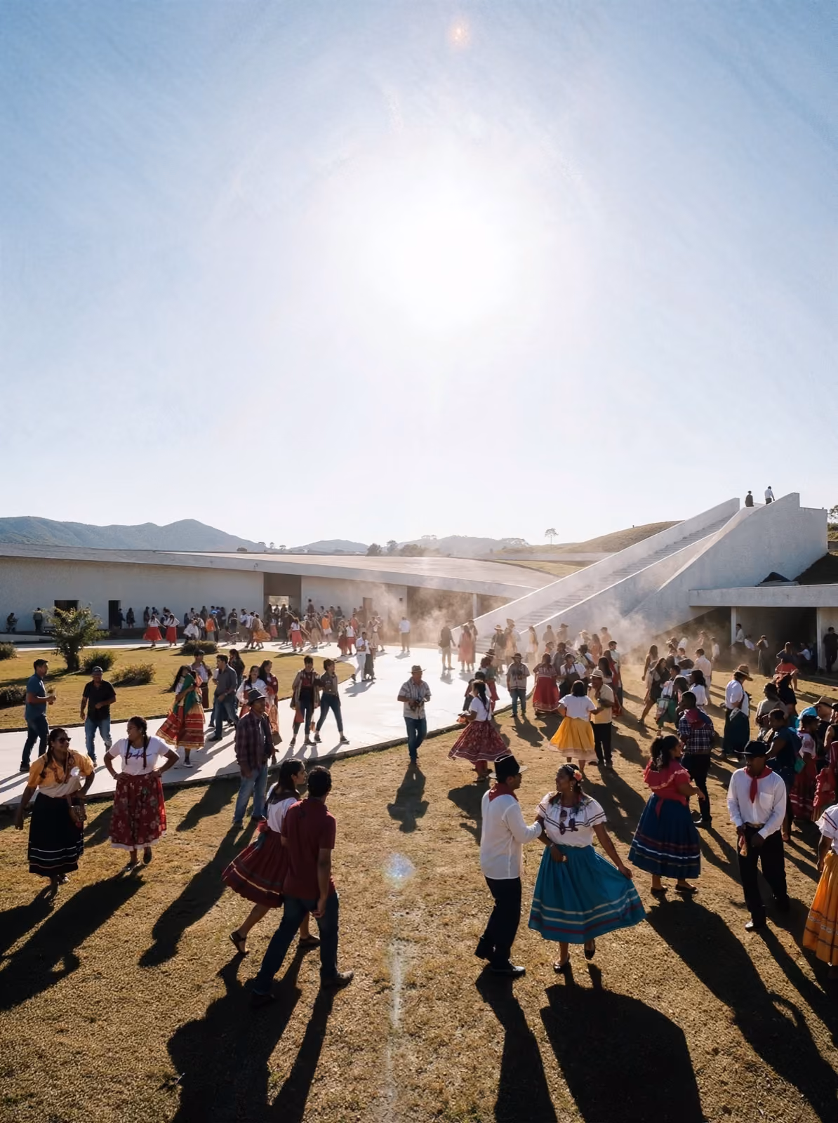 People in traditional colorful dresses dancing and socializing outdoors on grass near a modern white building.