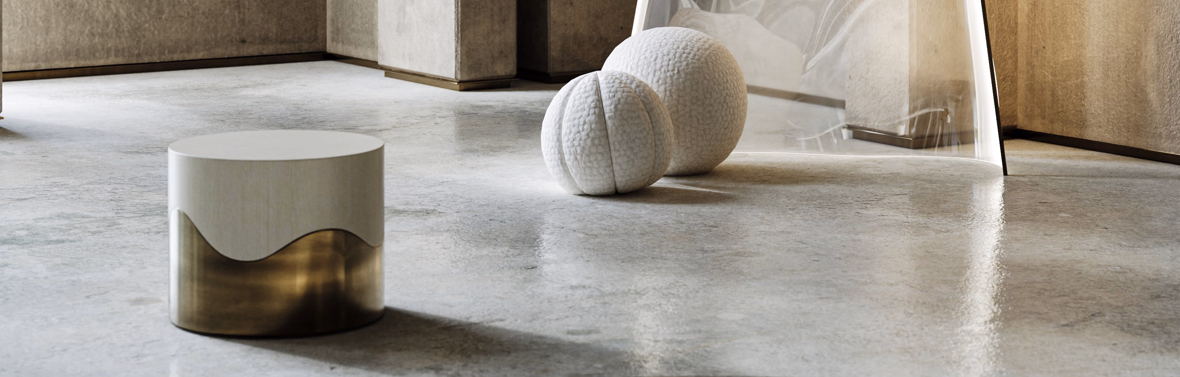 Modern stool with white top and metallic gold base on polished concrete floor near two textured white spheres.