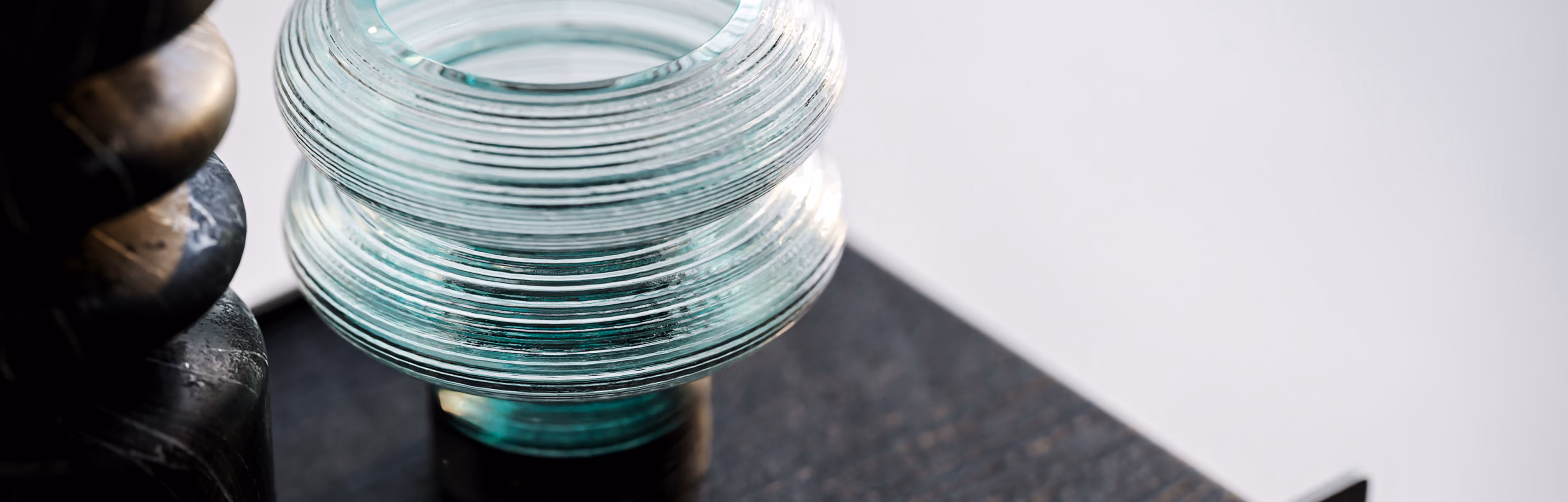 Close-up of a translucent textured glass object on a dark surface with a blurred background.