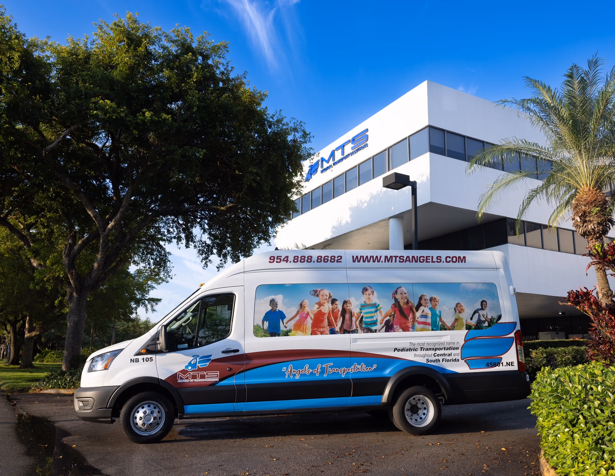 MTS pediatric transportation van with smiling children image parked outside company building.