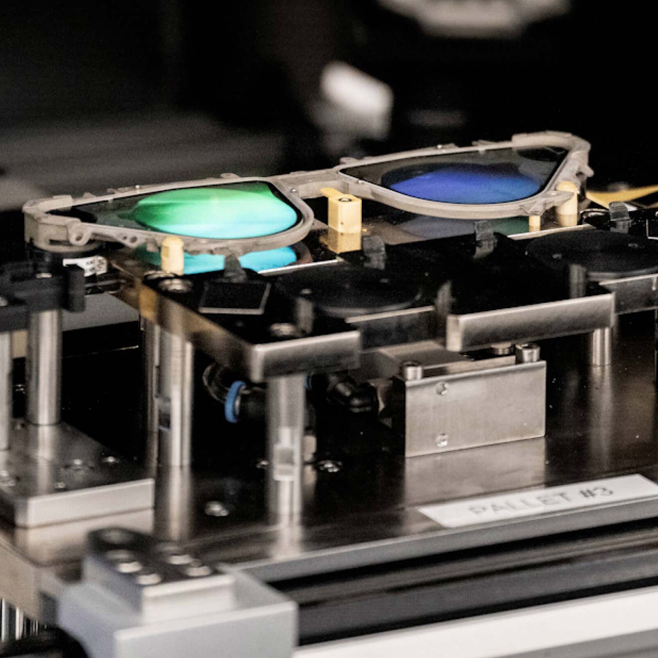 A pair of waveform lenses set in a frame, resting on a manufacturing cradle.