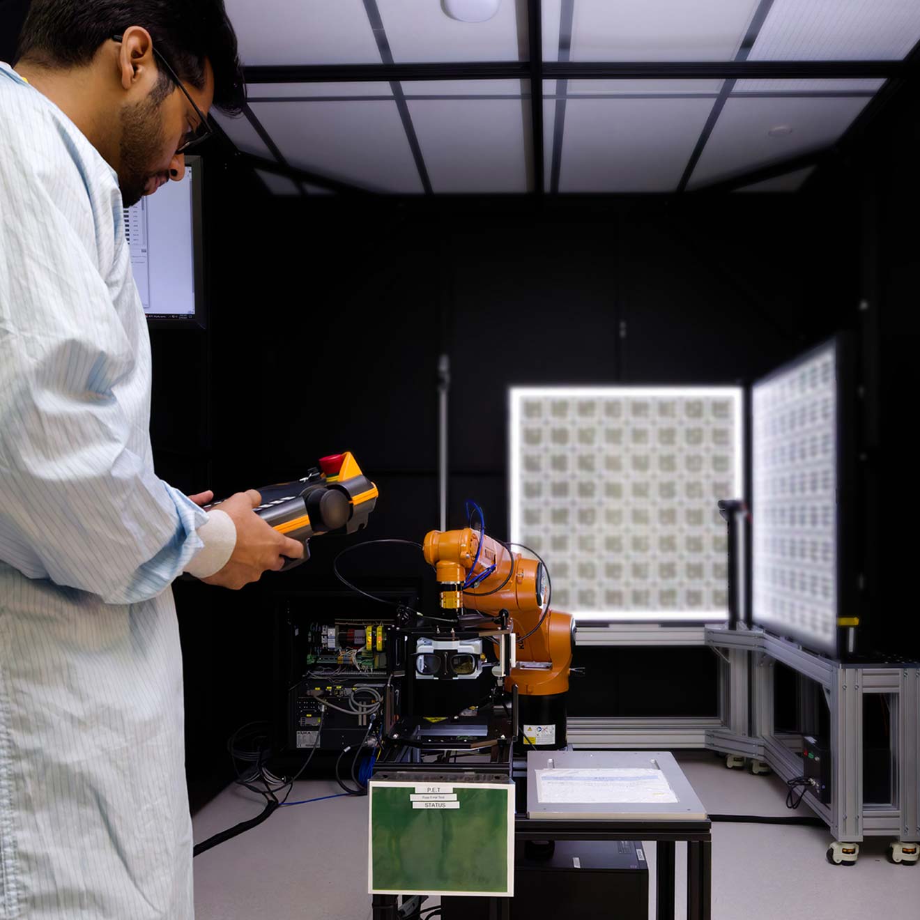 A robotic arm holds a pair of AR glasses while a technician prepares them for calibration.
