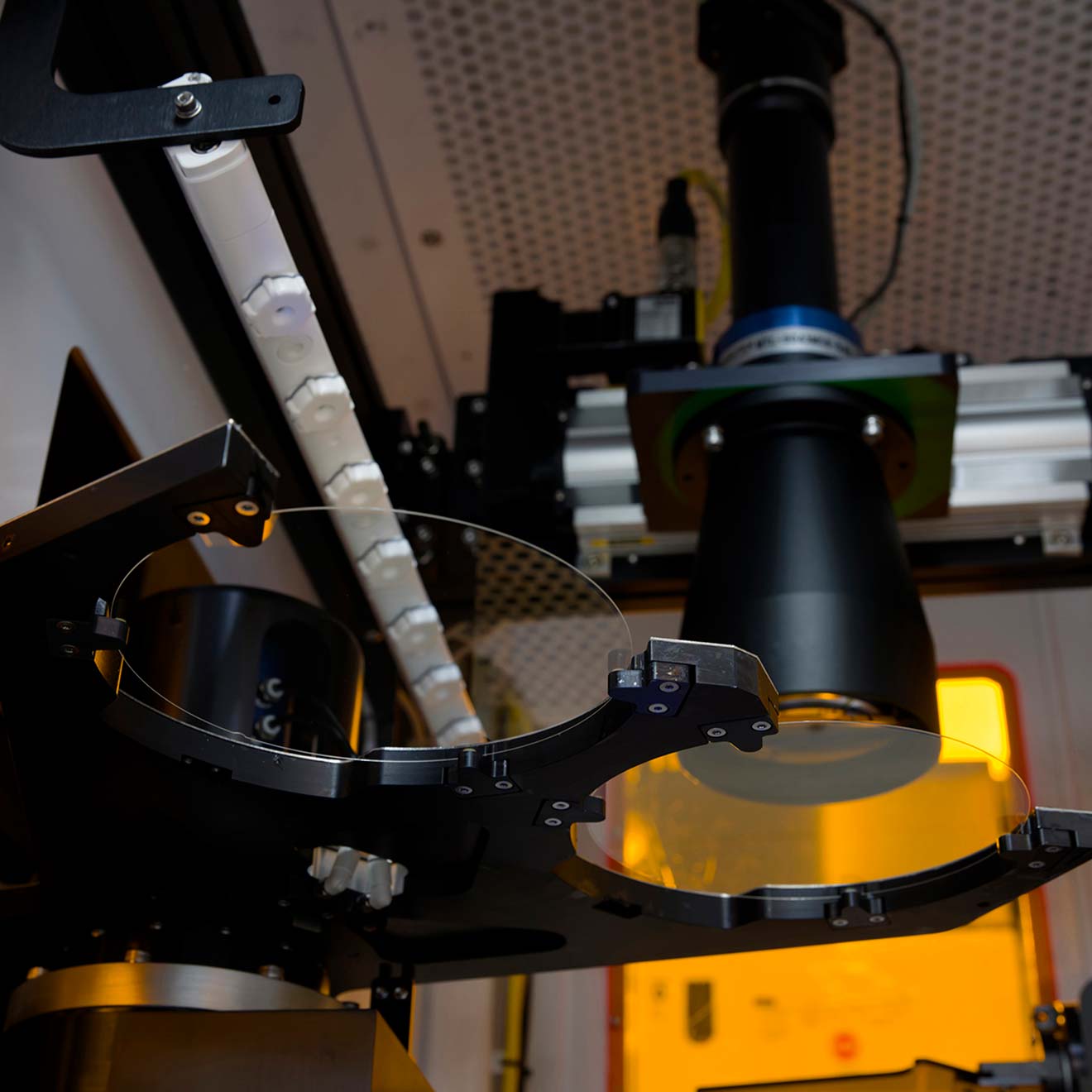 Two glass waveguide wafers during inspection inside a custom lithography machine.