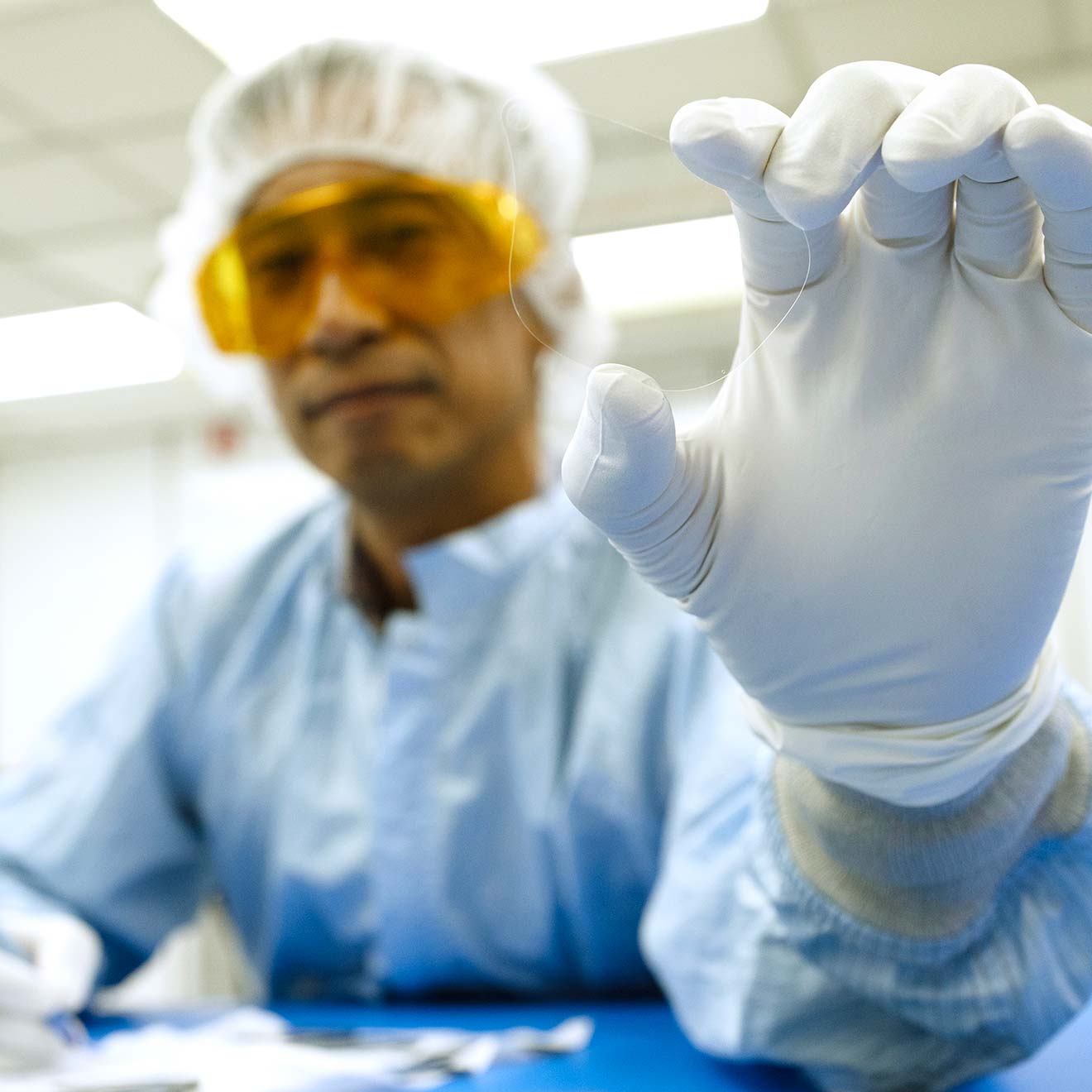 A smiling Magic Leap employee holds a single waveguide lens carefully in his gloved hand.