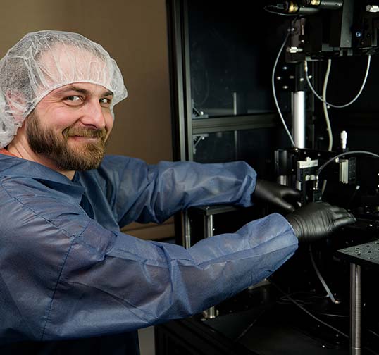 A smiling Magic Leap employee places device components into machine during the display prototyping process.