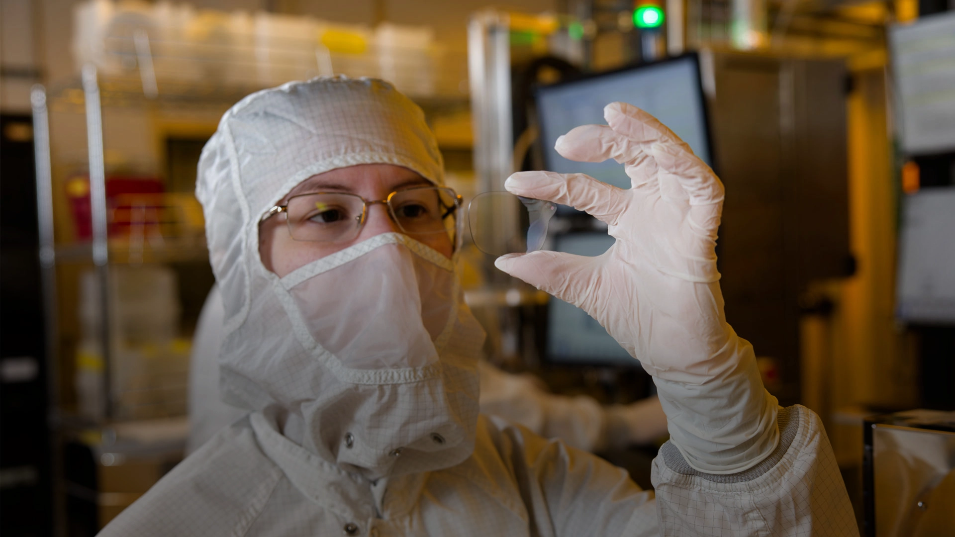 A gloved Magic Leap engineer in a clean room holds up a pristine waveguide.