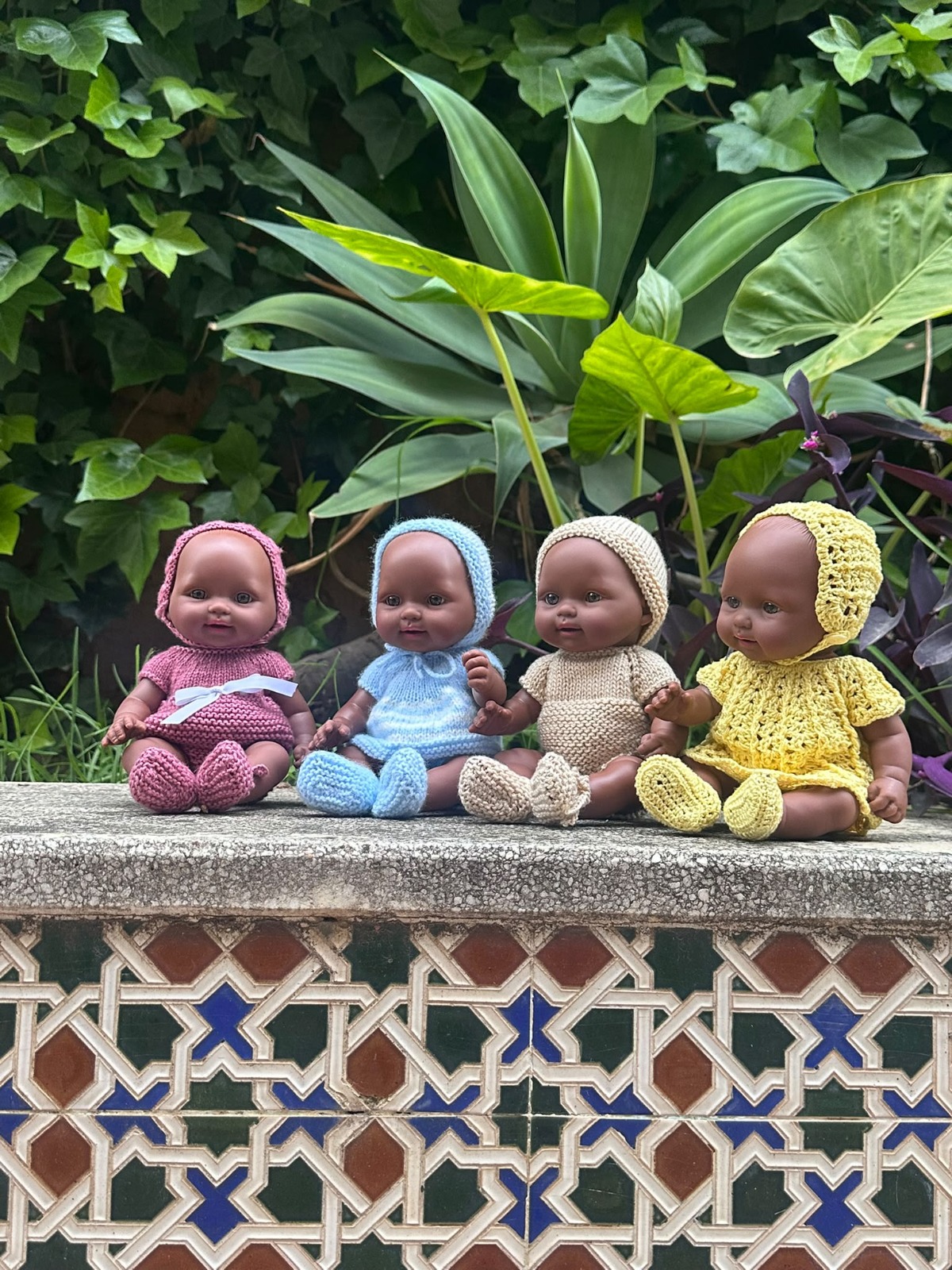 Cuatro muñecas Terezinha con conjuntos tejidos a mano de distintos colores