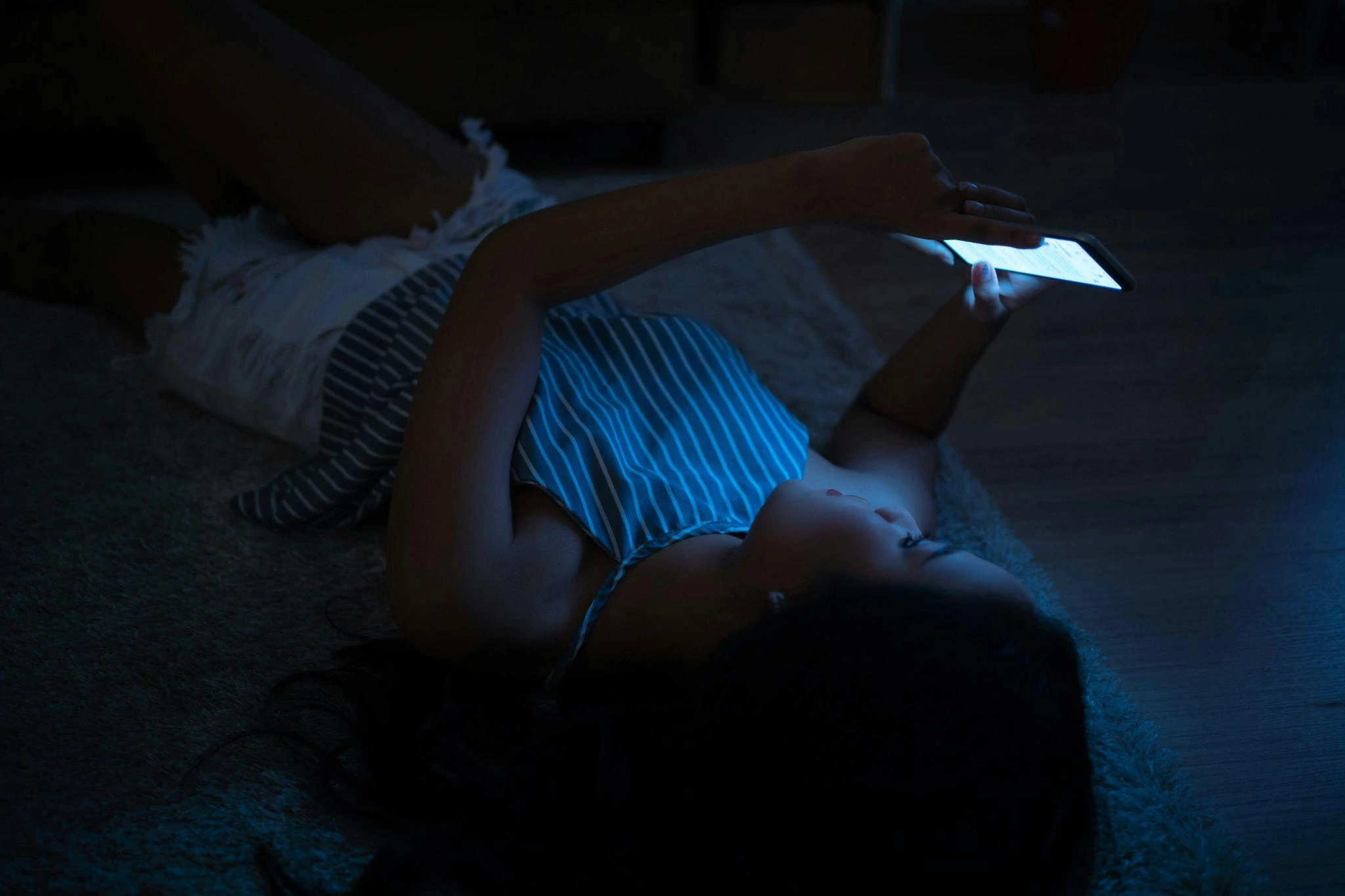 Someone laying in bed using a phone in the dark